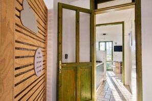 A wooden door with a sign, a kitchen area with a stove and chairs, and a tiled floor.