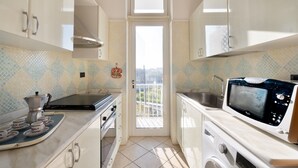 A compact kitchen with a microwave, stove, sink, and a small window.