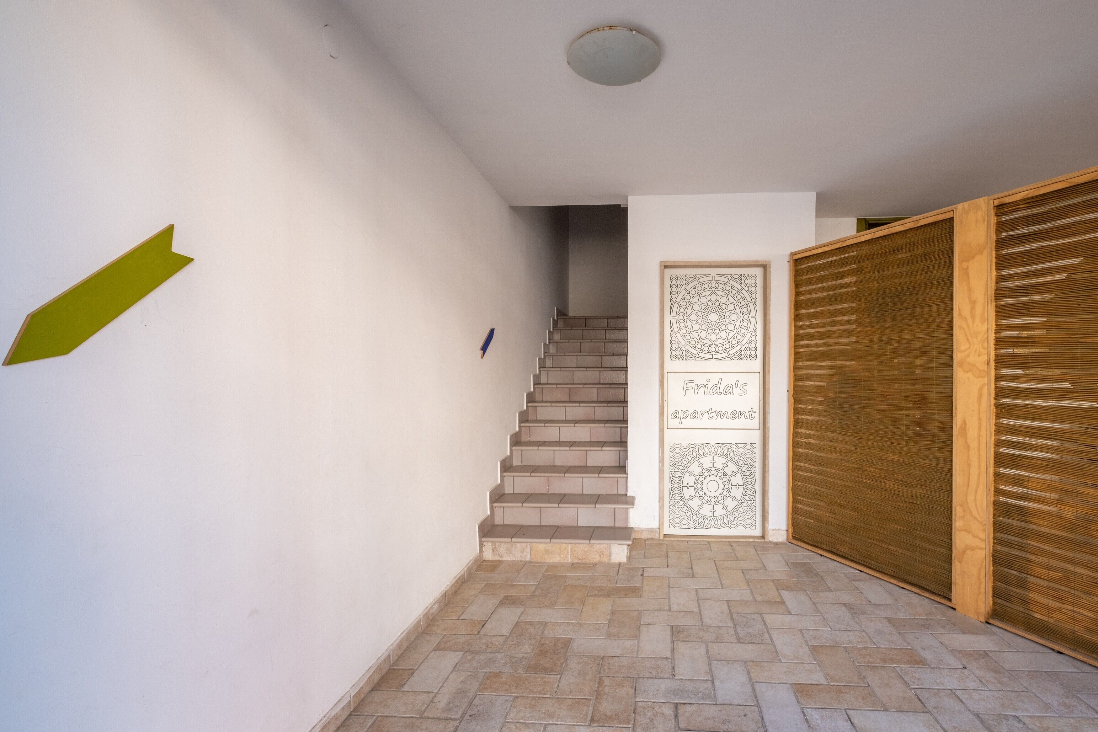Una escalera que lleva a un apartamento con una puerta con diseño y un persiano de madera.