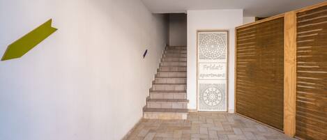Una escalera que lleva a un apartamento con una puerta con diseño y un persiano de madera.