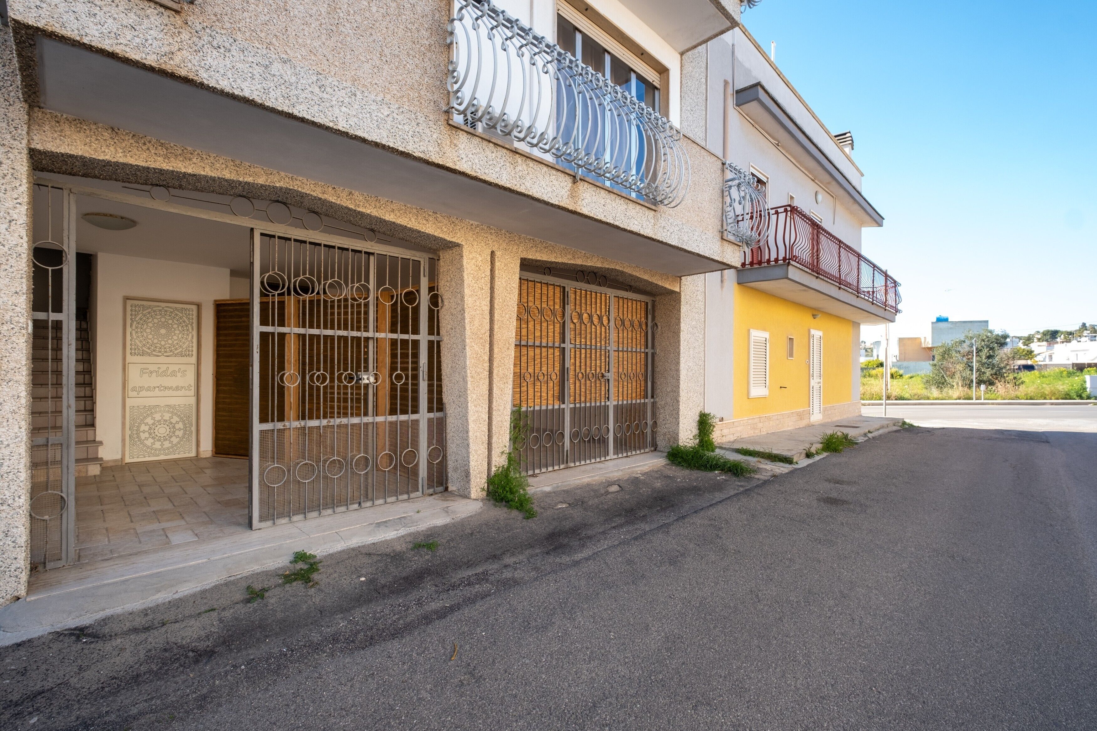 A two-story building with a balcony, a gated entrance, and a clear sky.