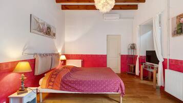 A bedroom with a bed, bedside lamps, a radiator, a television, and a door.