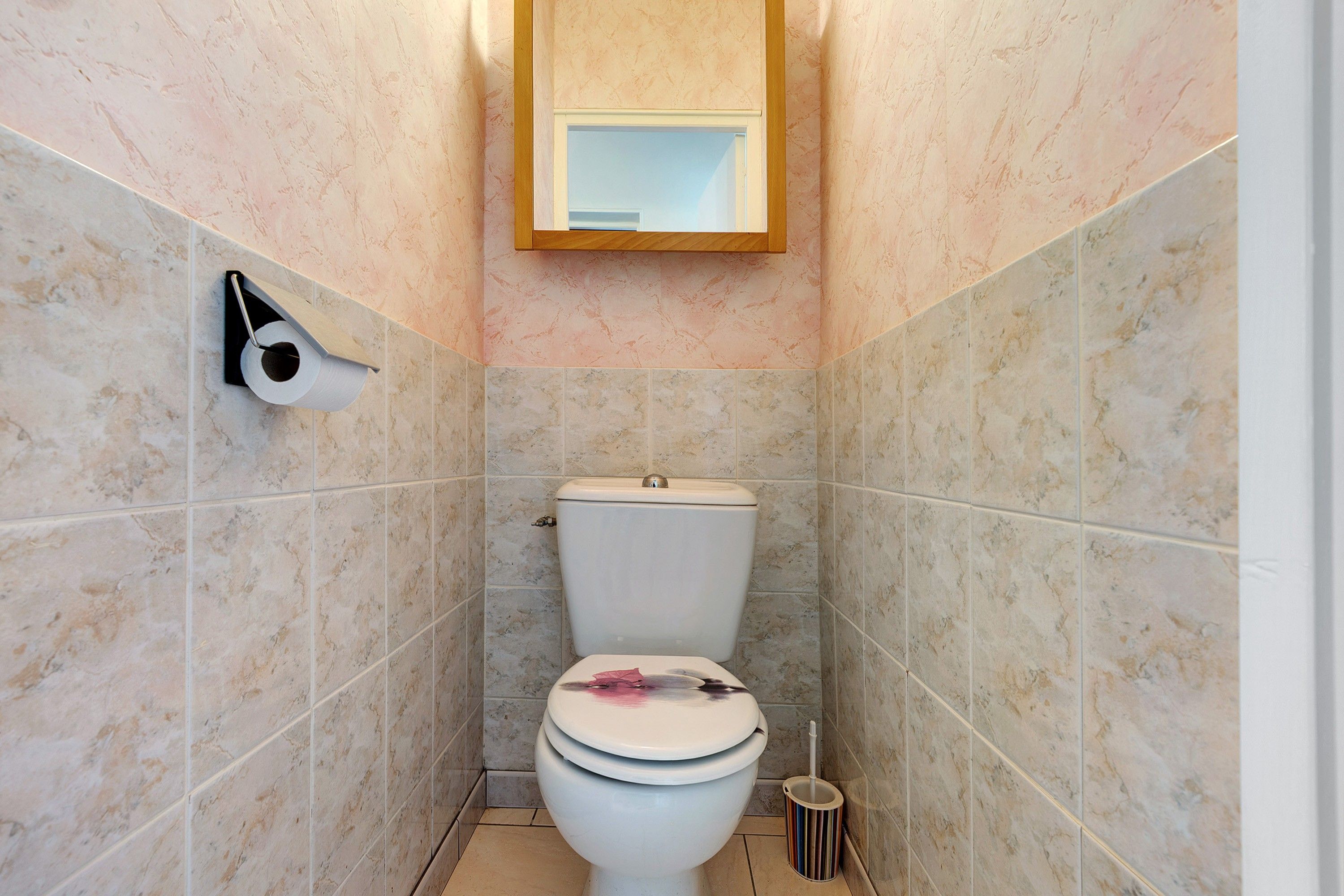 Een badkamer met een toilet, toiletrolhouder en een bidet.