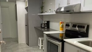 A modern kitchen with stainless steel appliances, grey cabinets, and a tiled floor.
