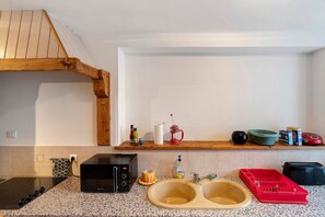 A kitchen with a microwave, double sink, wooden shelf, and various kitchen items. - Terre Happy – Country House with Shared Pool in Ribérac (Ribérac)