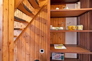 Un intérieur en bois avec un escalier en colimaçon, des étagères remplies d’ustensiles de cuisine et un fer à repasser Philips Easycare.
