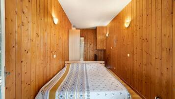 A narrow hallway with wooden walls and a patterned bedspread.