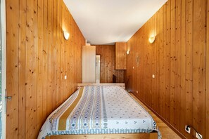 Un couloir étroit aux murs en bois et orné d’une couvre-lit à motifs.