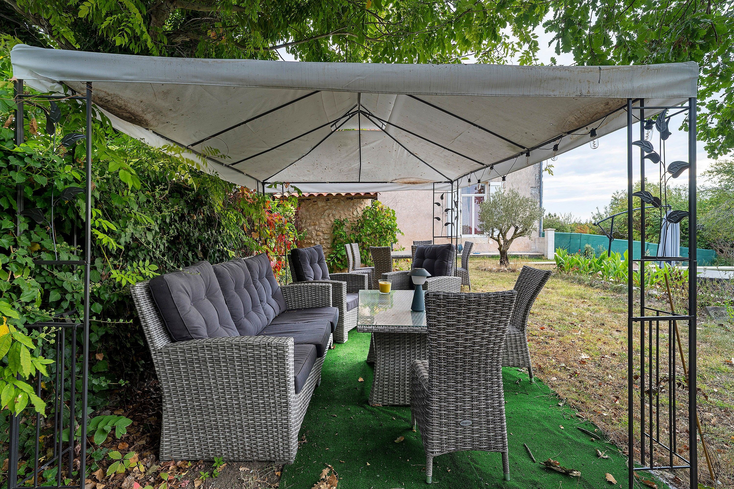 An outdoor patio with wicker furniture, a table, and a canopy.