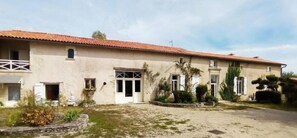 A two-story building with a red-tiled roof, a front entrance with glass doors, and a small balcony on the left side. - Room 'Chambre B' with Shared Pool, Wi-Fi and Air Conditioning (Ribérac)
