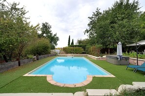 A rectangular swimming pool with a surrounding grassy area, a hot tub, and a covered seating area. - Room 'Chambre B' with Shared Pool, Wi-Fi and Air Conditioning (Ribérac)