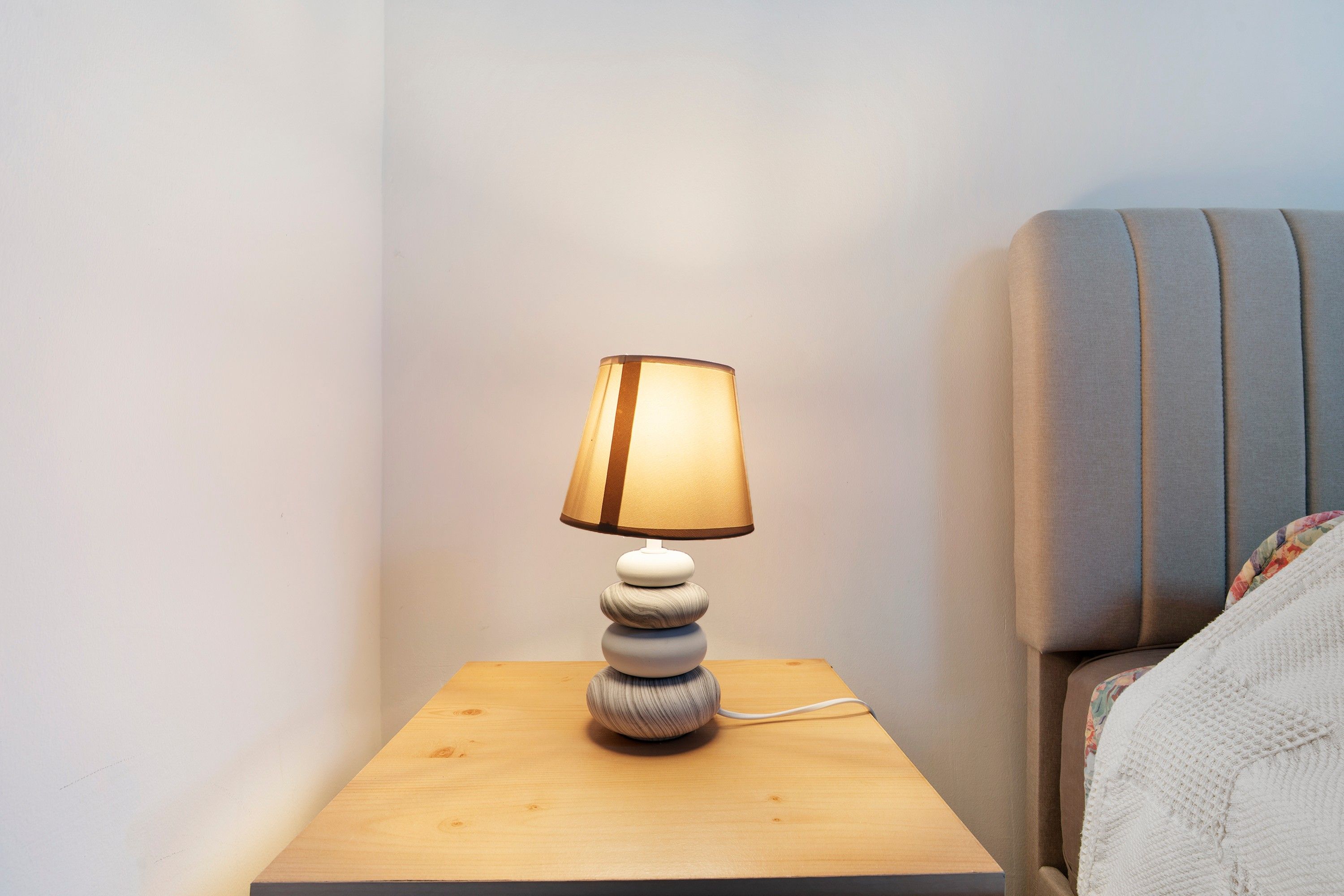 Une table de chevet avec une lampe, une table de nuit en bois et une tête de lit.