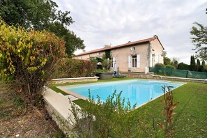 A house with a swimming pool, surrounded by greenery and a stone wall. - Room 'Chambre B' with Shared Pool, Wi-Fi and Air Conditioning (Ribérac)