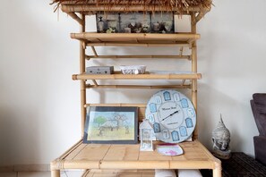A bamboo shelf with various decorative items including a clock, a framed picture, and small containers. - Room 'Chambre B' with Shared Pool, Wi-Fi and Air Conditioning (Ribérac)