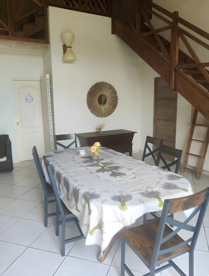 A dining area with a table set for six, a decorative mirror, and a staircase. - Guest House 'Chambre C' with Shared Pool, Wi-Fi and Air Conditioning (Ribérac)