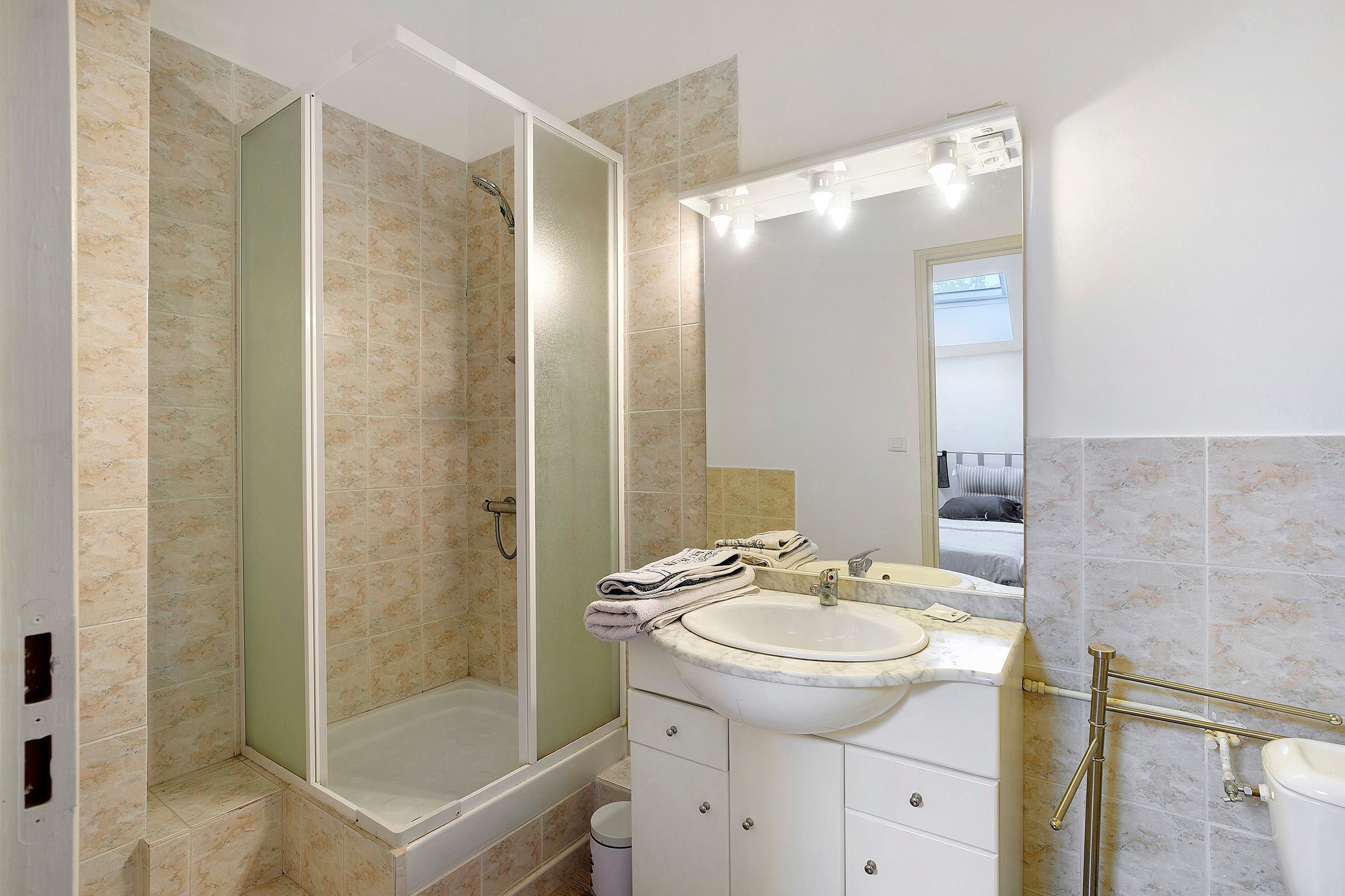Une salle de bain avec une douche à parois de verre, un lavabo et un miroir.