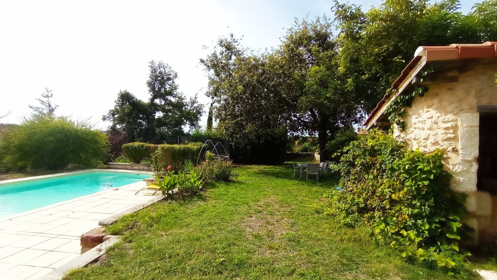 A swimming pool, grassy yard, and stone building.