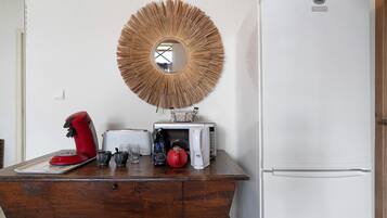 A kitchen with a white refrigerator, a wooden cabinet, a red coffee maker, a toaster, and a bag of coffee.