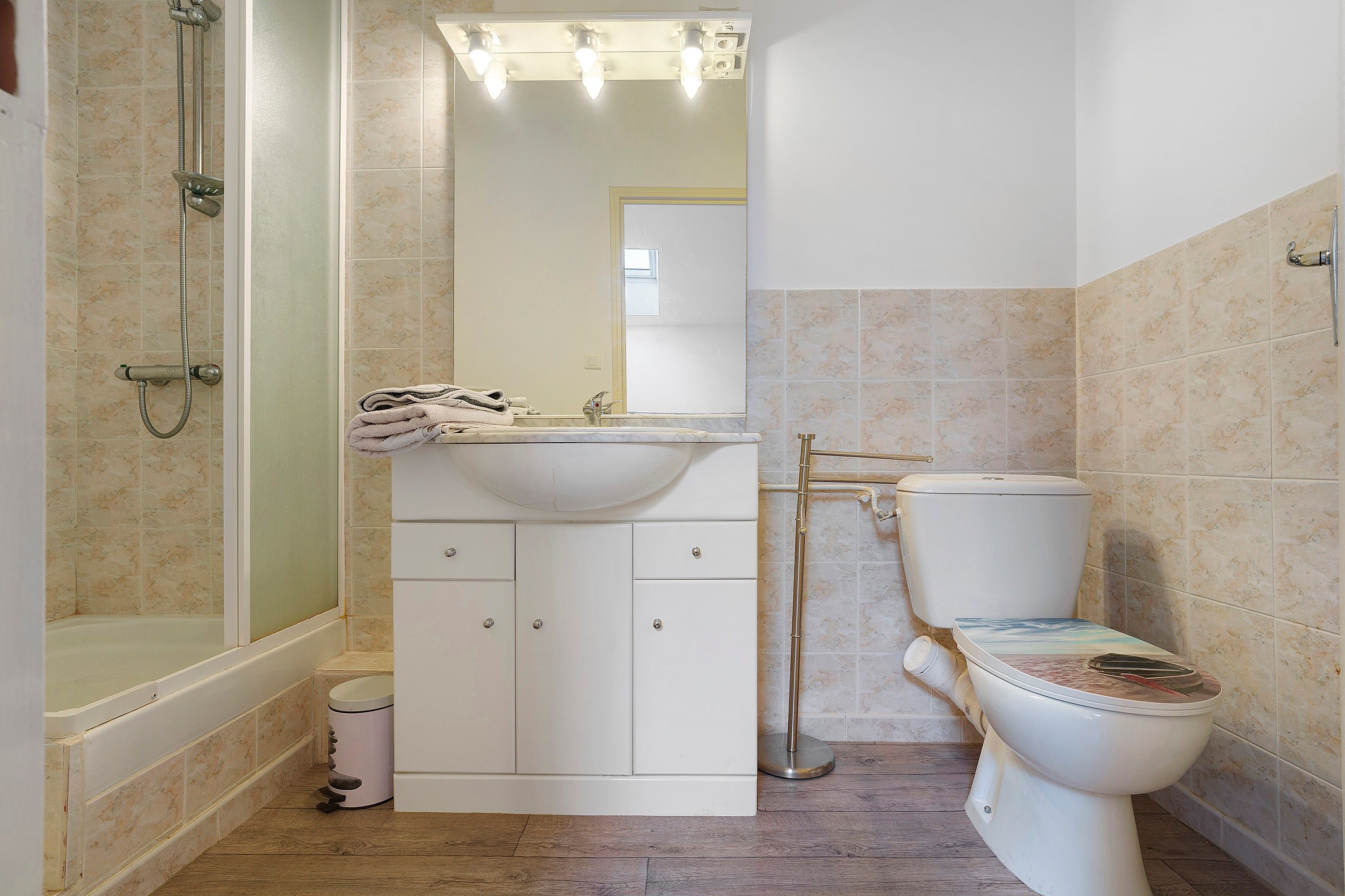 A bathroom with a shower, sink, toilet, and a mirror.