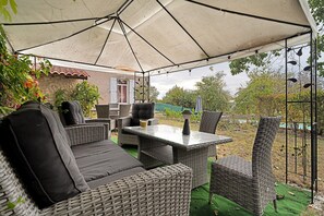 An outdoor patio with wicker furniture, a table, and an umbrella providing shade. - Guest House 'Chambre C' with Shared Pool, Wi-Fi and Air Conditioning (Ribérac)