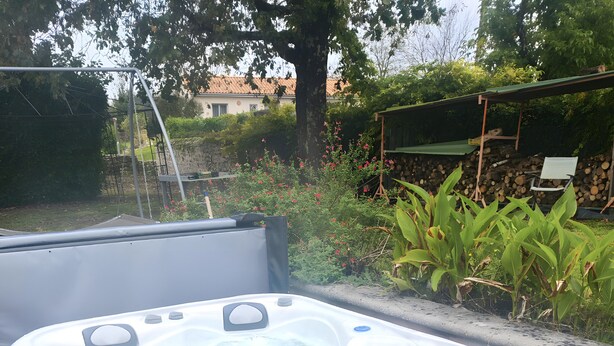 A hot tub with a control panel, surrounded by a garden with plants and a tree. - Guest House 'Chambre C' with Shared Pool, Wi-Fi and Air Conditioning (Ribérac)
