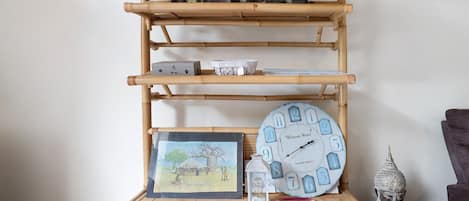 A bamboo shelf with various decorative items including a clock, a framed picture, and small containers.