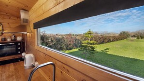 A wooden interior with a kitchen area, a window with a view of a green landscape and trees. - Cottage 'Casa Da Lagoa Pateira' with Private Pool, Wi-Fi and Air Conditioning (Fermentelos)