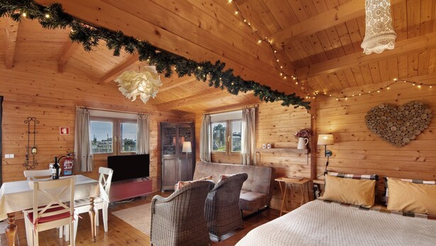 A cozy log cabin room with a dining area, sofa, and a heart-shaped woodpile decoration. - Cottage 'Casa Da Lagoa Pateira' with Private Pool, Wi-Fi and Air Conditioning (Fermentelos)