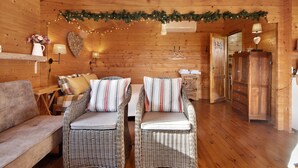 A cozy log cabin interior with wicker chairs, a sofa, a heart-shaped wall decoration, and a garland. - Cottage 'Casa Da Lagoa Pateira' with Private Pool, Wi-Fi and Air Conditioning (Fermentelos)