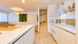 Eine moderne Küche mit weißen Schränken, einem eingebauten Herd und einer Holztreppe, die zu einer weiteren Ebene führt.