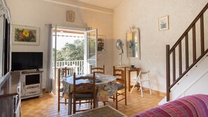 A dining area with a round table, chairs, a television, and a staircase. - Apartment 'Duplex' with Sea View and Balcony (Grosseto-Prugna)