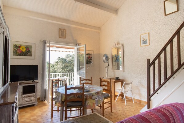 A dining area with a round table, chairs, a television, and a staircase.