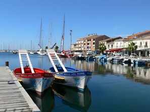 Una marina con barche ormeggiate, un molo di legno e edifici sullo sfondo.