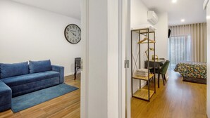 A modern room with a sofa, a dining area, and a bed.