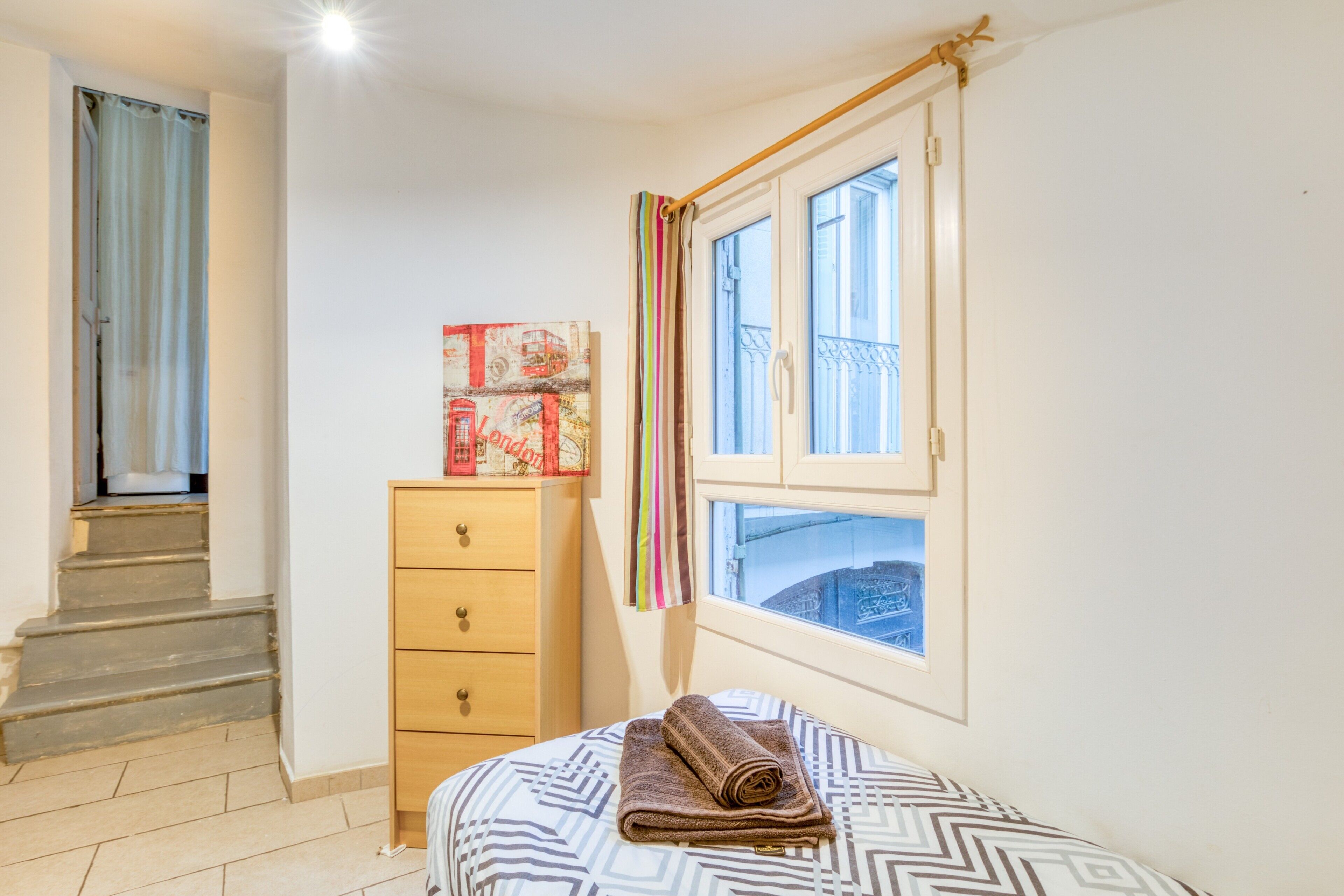 Ein Schlafzimmer mit einem Bett, einem Schminktisch, einem Fenster mit Blick und einer Treppe.