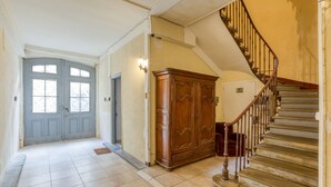 A hallway with a wooden cabinet, a staircase, and a blue door.