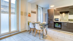 A modern kitchen with a dining area, large windows, and a view of the outside.