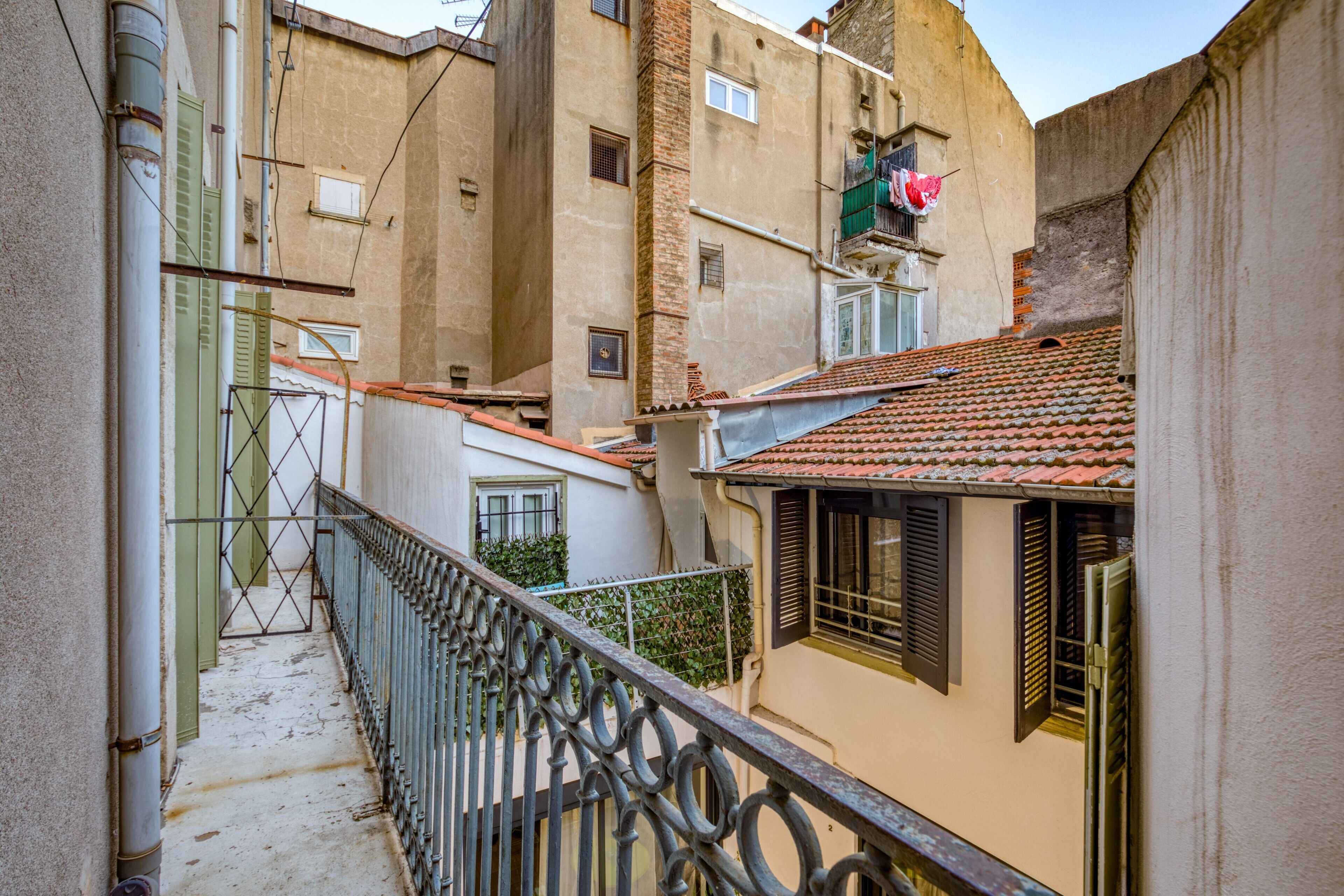 A narrow alleyway with buildings on either side, a metal railing, and a tiled roof.