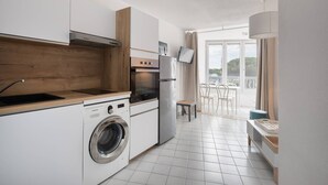 A modern kitchen with a washing machine, oven, and a TV mounted on the wall.
