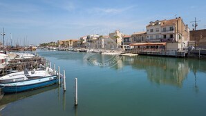 A marina with boats docked, buildings with balconies, and a clear sky.
