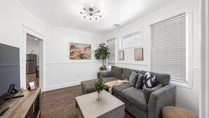 A modern living room with a grey sofa, a coffee table, and a TV on a wooden stand.