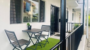 A balcony with a table and chairs, a potted plant, and a view of the street. - Charming 3-bedroom house with AC and WiFi in amazing Suva (Suva)