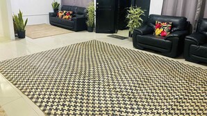 A modern living room with a patterned rug, black leather sofas, and potted plants. - Charming 3-bedroom house with AC and WiFi in amazing Suva (Suva)