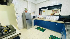 A compact kitchen with a refrigerator, microwave, stove, and blue cabinets. - Charming 3-bedroom house with AC and WiFi in amazing Suva (Suva)