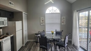 Una cocina con una mesa de comedor, sillas, microondas, refrigerador y estufa.