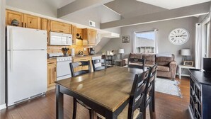 Eine moderne Küche mit Holzschränken, einem weißen Kühlschrank und einem Essbereich mit Holztisch und Stühlen.