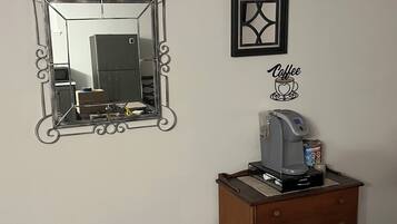 Une pièce avec un miroir, un tableau encadré, une machine à café et une commode en bois.