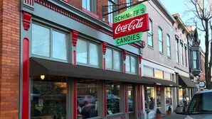 Una fachada con un letrero de Coca-Cola y un letrero de tienda de dulces.