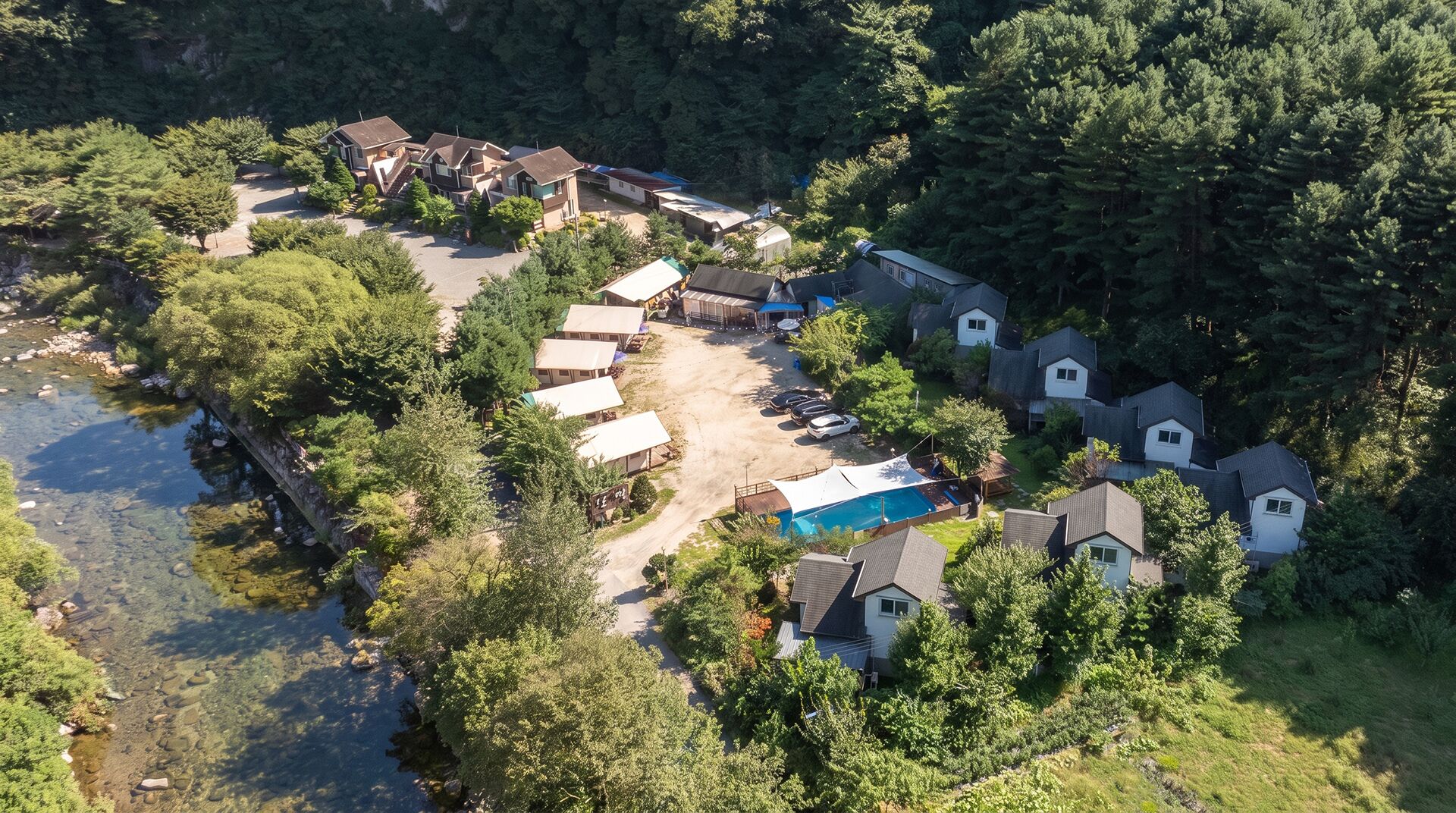 Vista aérea de una zona residencial con varias casas, una piscina y un pequeño cuerpo de agua.