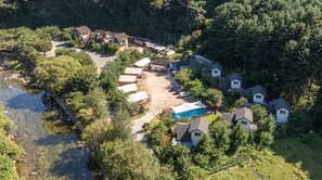 An aerial view of a residential area with multiple houses, a swimming pool, and a small body of water.